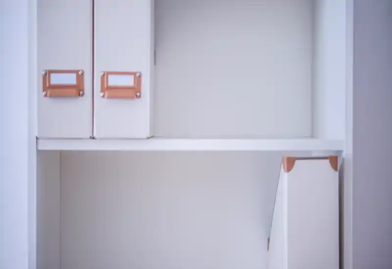 A close-up of a white shelving unit with document boxes and magazine files; neutral minimalist storage detail, no clear room context.