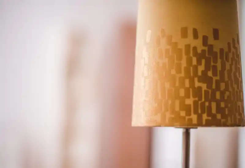 Close-up detail of a patterned lamp shade against a softly blurred background; the image focuses on lighting decor rather than showing a full room.
