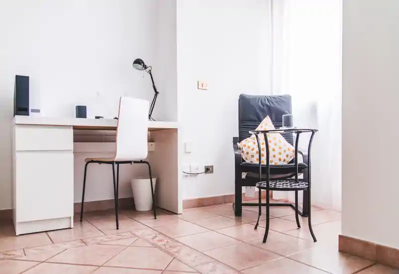 Bright, minimal living corner with a comfy armchair, side table and a small desk — perfect for relaxing or working by the window.