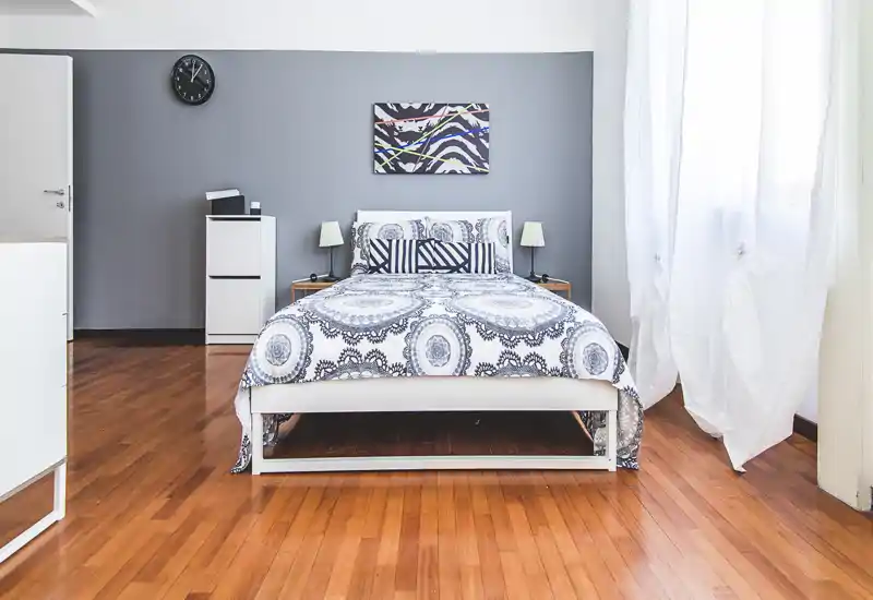 Bright, well-staged bedroom with a centrally placed double bed, patterned bedding and natural light from a large window — ideal for rental photos.