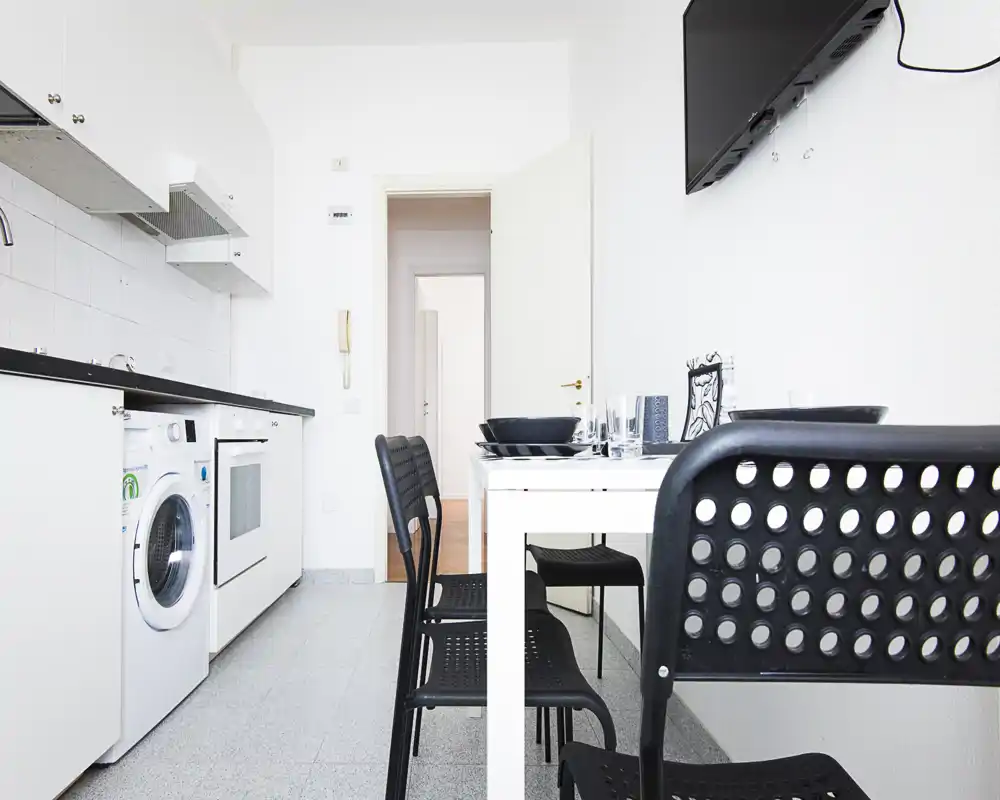 Bright, modern kitchen with integrated appliances and a small dining table set for four — ideal for compact city apartments.