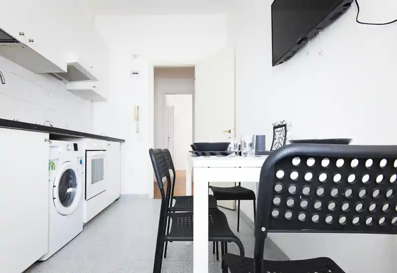 Bright, modern kitchen with integrated appliances and a small dining table set for four — ideal for compact city apartments.