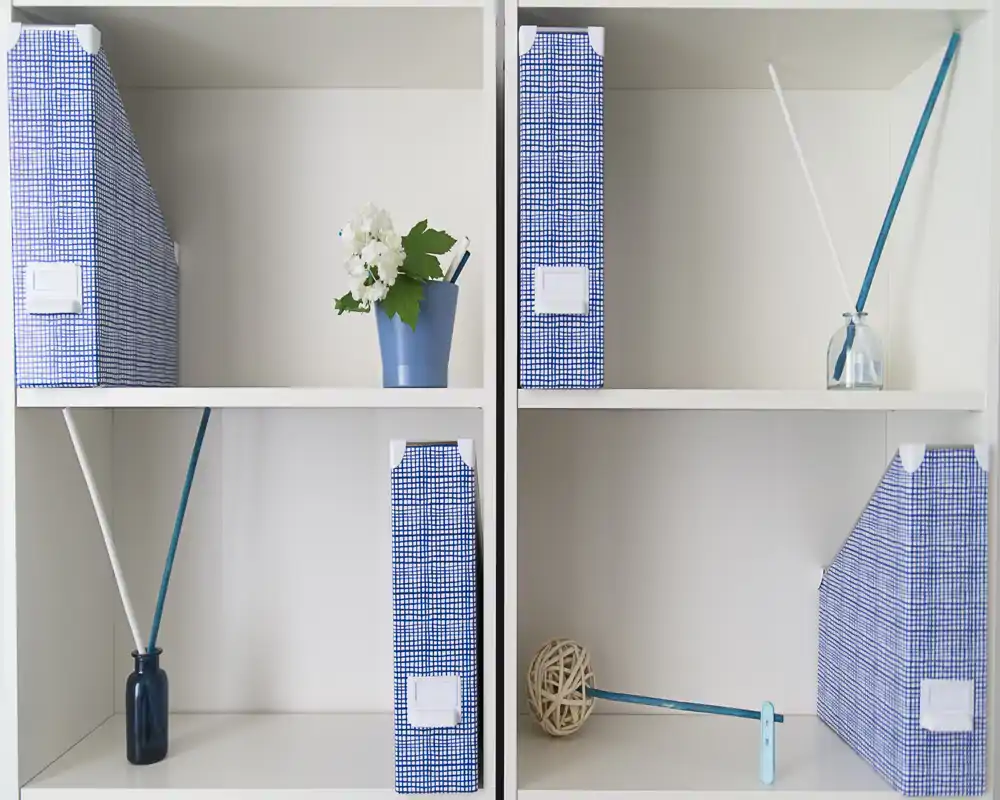Primo piano di una libreria bianca con portalistini blu a motivo e piccoli oggetti decorativi; l'immagine mette in risalto contenimento e styling, non una funzione di stanza specifica.