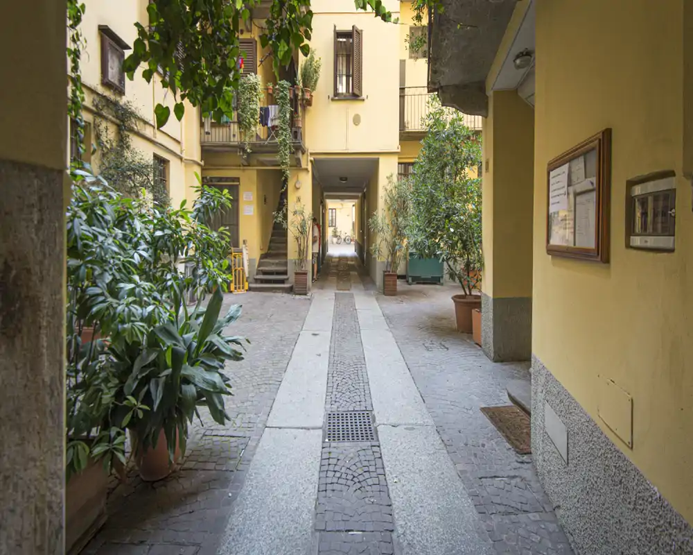 Charming internal courtyard with potted plants, walkway and passage to the building — ideal for showcasing shared outdoor space.