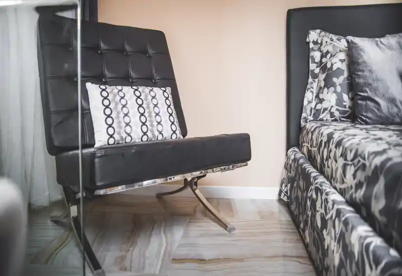 Stylish bedroom corner featuring a patterned bed with coordinating cushions and a modern black leather chair — bright, well-composed shot that highlights textures and contemporary decor.