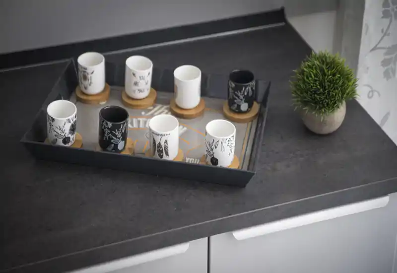 Close-up of a kitchen countertop styled with a decorative tray holding espresso cups and a small potted plant, ideal for showing kitchen details and styling.