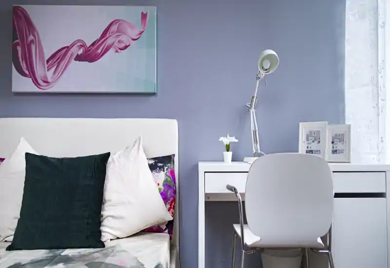 Bright, stylish bedroom corner with a white headboard, layered pillows and a tidy desk by the window — ideal for work and relaxation.