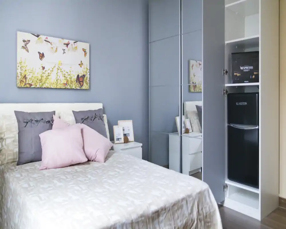 Camera da letto luminosa e curata, con letto matrimoniale, cuscini decorativi e una cabina con ante a specchio che amplia lo spazio. Toni pastello e un quadro minimale creano un’atmosfera rilassante e accogliente.