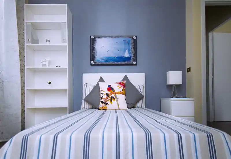 Camera da letto luminosa e ben arredata con letto centrale, cuscini decorativi e comodini coordinati; perfetta per foto di annunci.