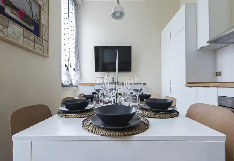 Bright, well-styled dining area with a table set for several guests; modern white cabinetry and warm accents create an inviting meal space.