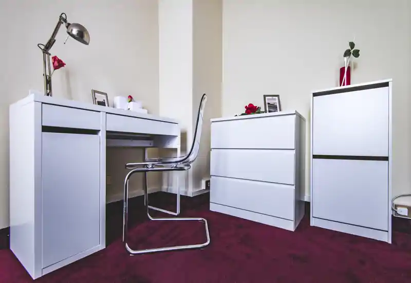 Compact, modern bedroom corner with white storage units and a minimalist desk; clear styling and decorative accents create a tidy, inviting space.
