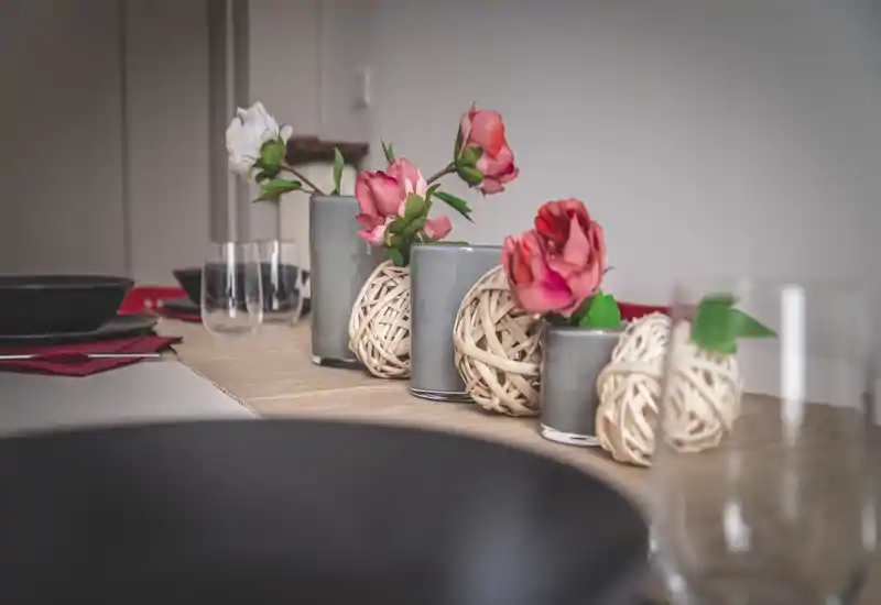 Gros plan d'une table à manger décorée avec des vases, des boules tressées et des couverts ; idéal pour illustrer la décoration de table et l'ambiance du repas.