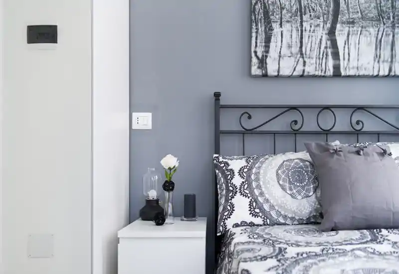 Stylish bedroom corner with patterned bedding, decorative pillows and a neat white bedside table; soft natural light and coordinated wall art create a calm, modern atmosphere.