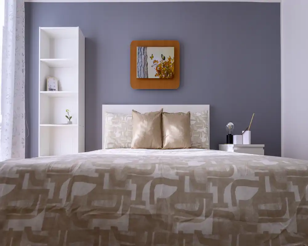 Bright, styled bedroom with a large bed front and neutral beige textiles, accented by a framed artwork and bedside shelving for a calm, welcoming atmosphere.
