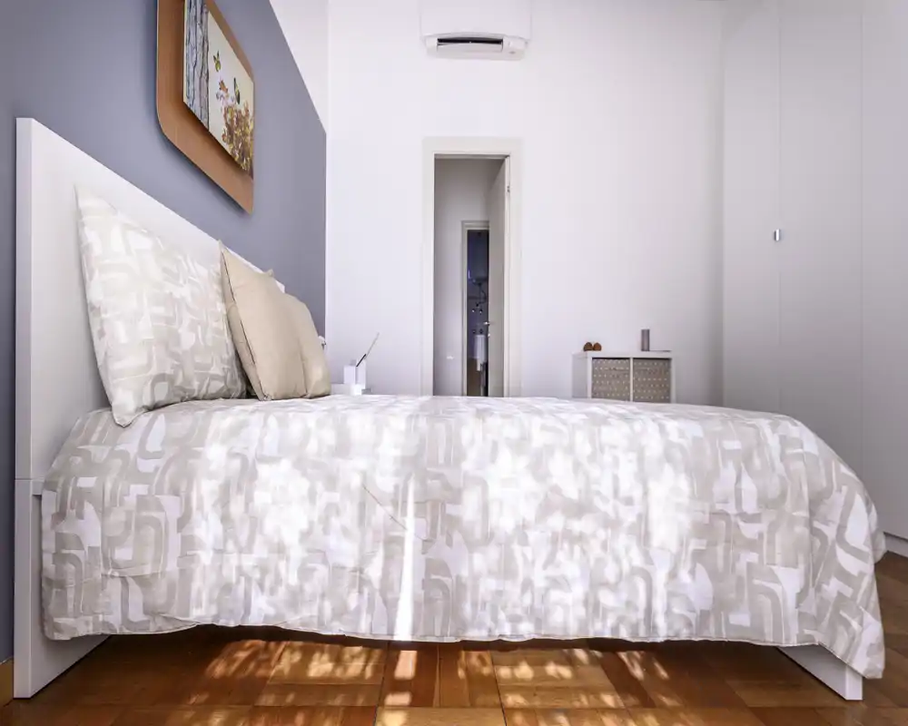 Bright, modern bedroom with a large bed facing the camera, neutral bedding and warm wooden floor; minimal decor and soft natural light create a calm, welcoming atmosphere.