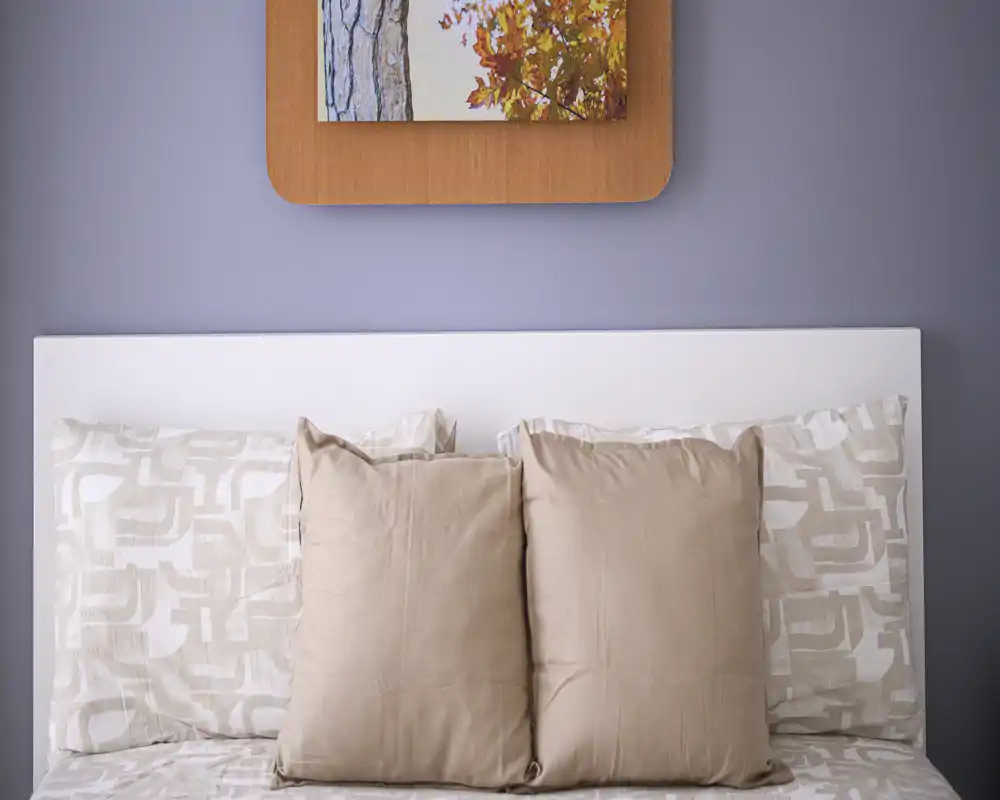 Bright, neatly styled bedroom headboard with neutral pillows and patterned linens creating a calm, inviting atmosphere.