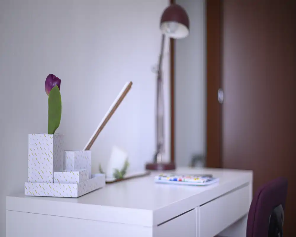 Bright, minimal desk area with a decorative vase, task lamp and a chair—ideal for a compact workspace or study corner.