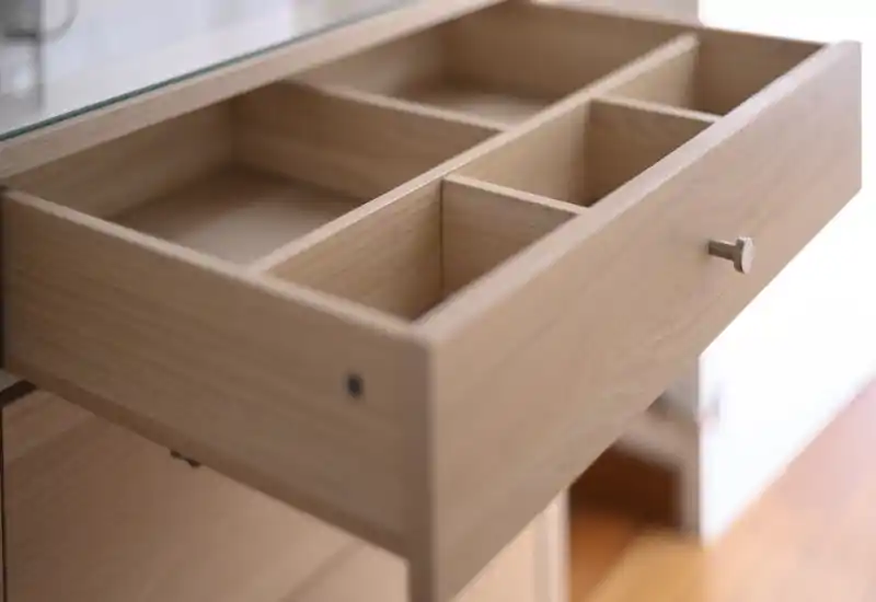 Gros plan sur un tiroir en bois ouvert avec compartiments intégrés et bouton en métal; photo centrée sur le détail, adaptée à une fiche produit mobilier.