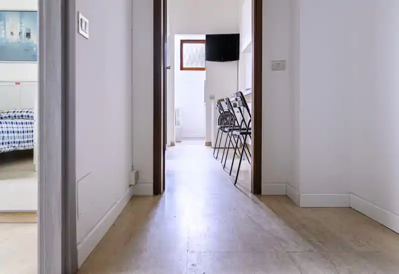 Narrow corridor/entrance view leading to other rooms; simple, clean hallway with wood flooring and natural light at the far end.