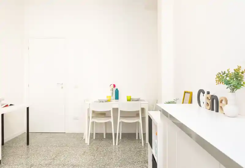 Angolo pranzo luminoso e minimal con un piccolo tavolo bianco apparecchiato e semplici elementi decorativi — ideale per un appartamento compatto.