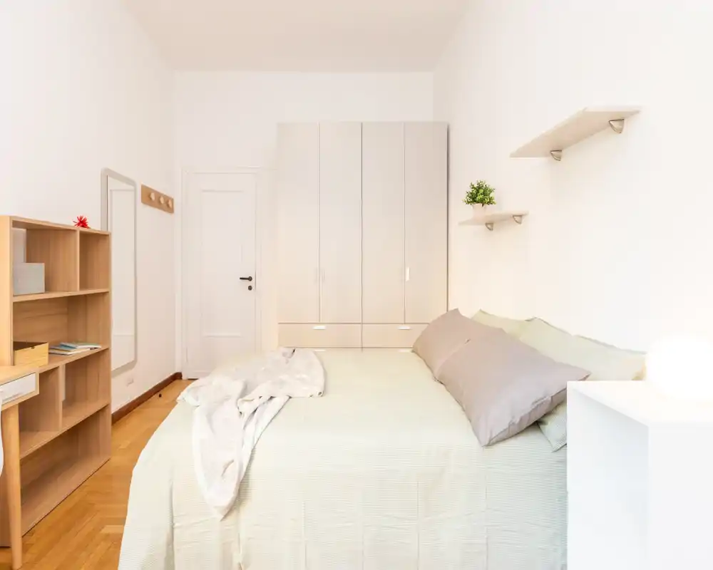 Bright, well-styled bedroom with a large bed, neutral linens and warm wooden flooring creating a calm, inviting atmosphere.