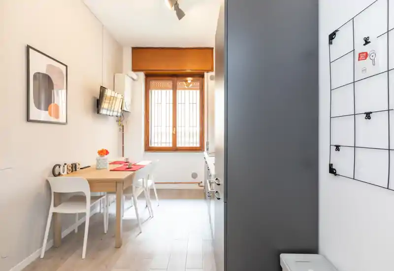 Cocina luminosa y compacta con una mesa para dos, armarios modernos y una ventana grande que aporta luz natural — ideal para desayunos acogedores o comidas rápidas.