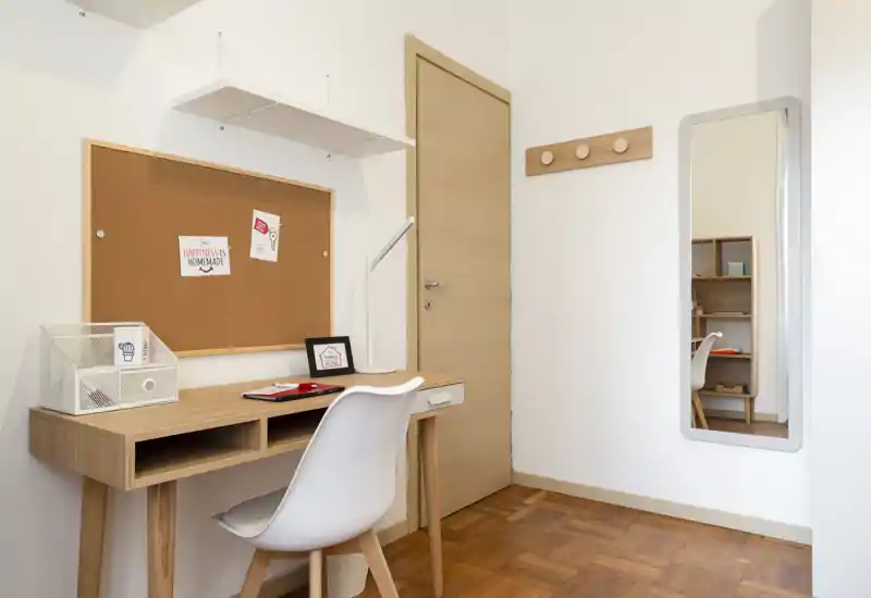 Coin bureau lumineux et minimaliste avec bureau en bois, chaise blanche, panneau en liège et miroir mural — un espace de travail propre et bien éclairé, idéal pour le télétravail ou les études.