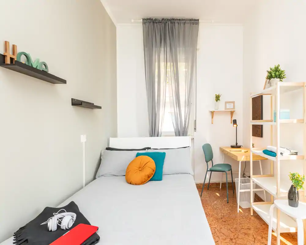 Chambre lumineuse et bien mise en scène avec lit double, coussins décoratifs et un petit bureau près de la fenêtre — idéale pour une annonce mettant en avant un espace nuit cosy et ensoleillé.