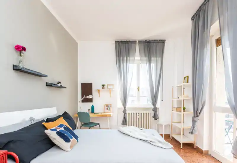 Camera da letto luminosa e arredata con un ampio letto, tessili morbidi e una finestra che lascia entrare molta luce naturale — perfetta per gli annunci.