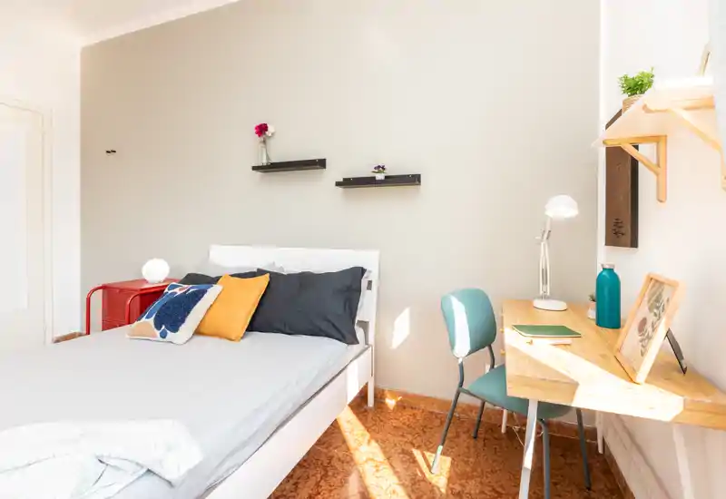 Chambre lumineuse et bien agencée avec un lit double, coussins décoratifs et un petit bureau près de la fenêtre—parfaite pour un séjour confortable et le télétravail.