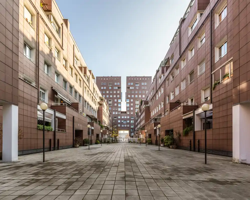 Espacioso patio residencial enmarcado por bloques de apartamentos simétricos, pavimento y farolas — ideal para áreas exteriores comunes y circulación.