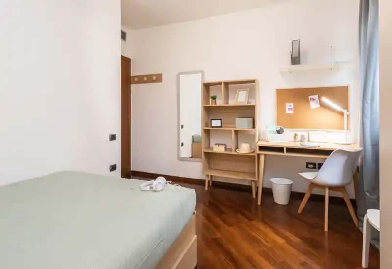 Bright, neatly staged bedroom with a single bed, wooden floor and a tidy desk area — ideal for a student or solo traveler.