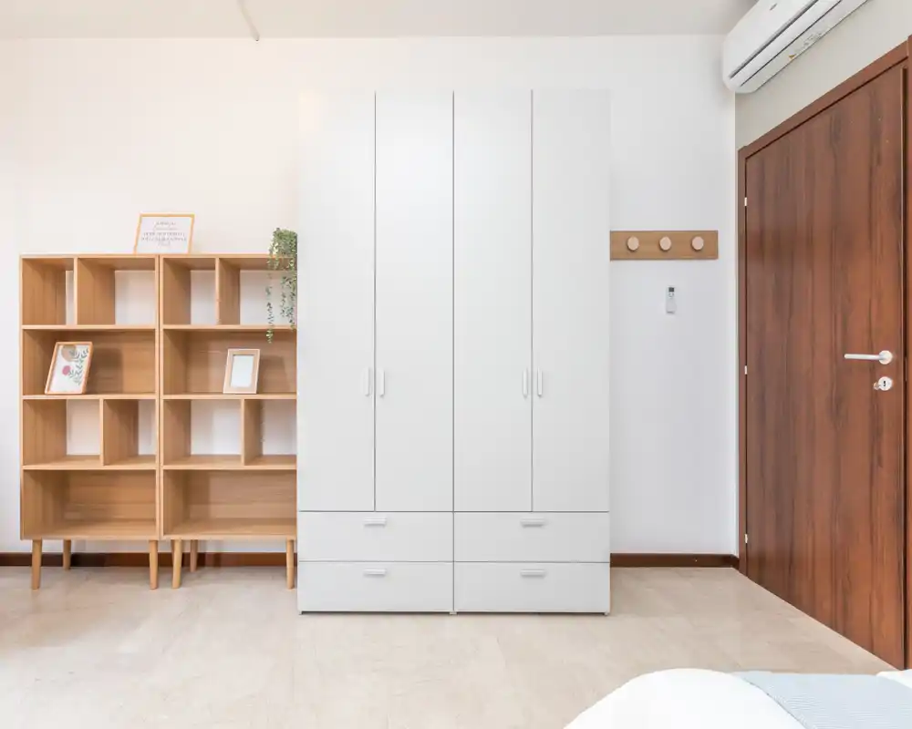 Rincón de dormitorio minimalista con armario blanco, estanterías de madera y vista parcial de la cama; luminoso y limpio, ideal para anuncios.