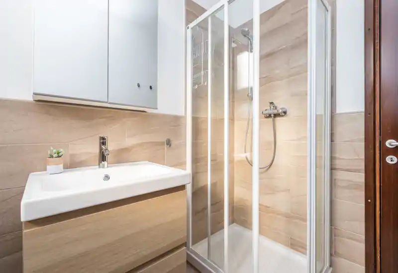 Bright, modern bathroom with a glass-enclosed shower and a wall-mounted sink vanity with mirror cabinet.