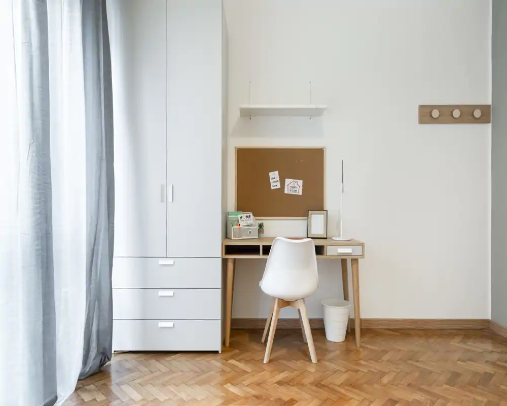 Angolo camera chiaro e minimale con scrivania compatta, sedia e armadio — ideale come piccolo spazio studio nella zona notte.