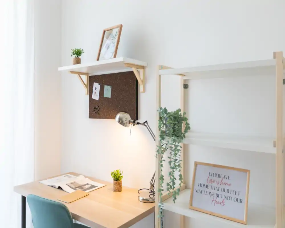 Bright, minimalist home workspace with a wooden desk, task lamp, small plants and shelving — ideal for focused work or study.