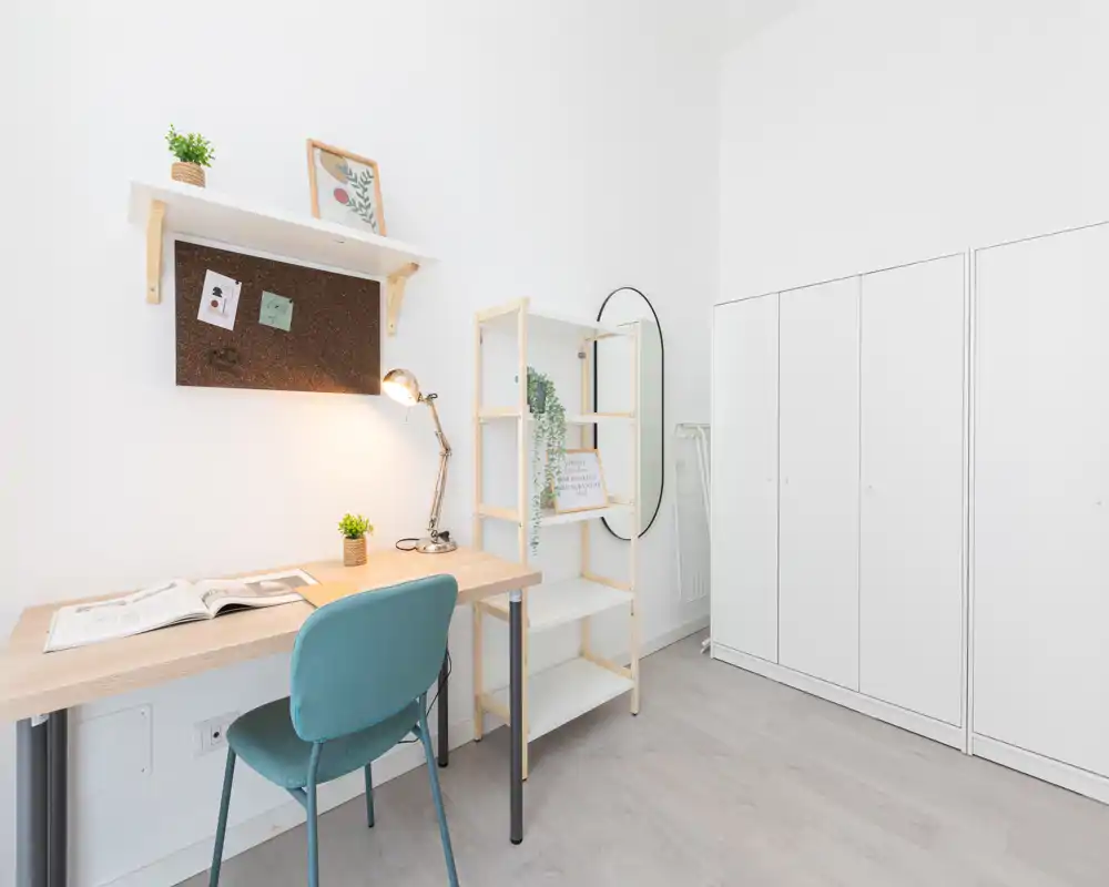 Minimal, bright bedroom corner with a study desk, chair, shelving and a wardrobe; neat Scandinavian-style decor and lots of white space.