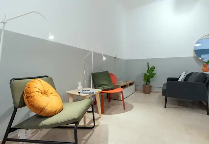 Area soggiorno elegante con poltrone moderne, un piccolo divano, tessili caldi e illuminazione accurata che rendono lo spazio d'attesa accogliente e contemporaneo.
