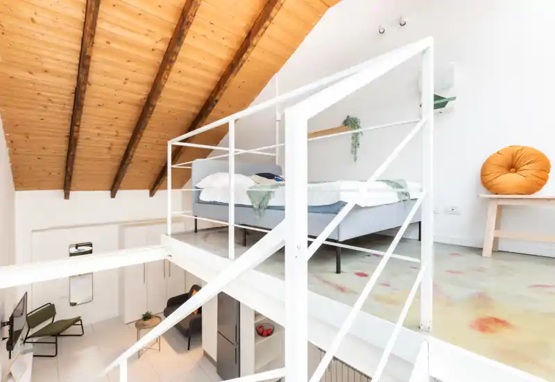 Dormitorio en entreplanta luminoso con cama doble, techo de madera abovedado y decoración minimalista de estilo nórdico — ideal para una acogedora estancia en loft.