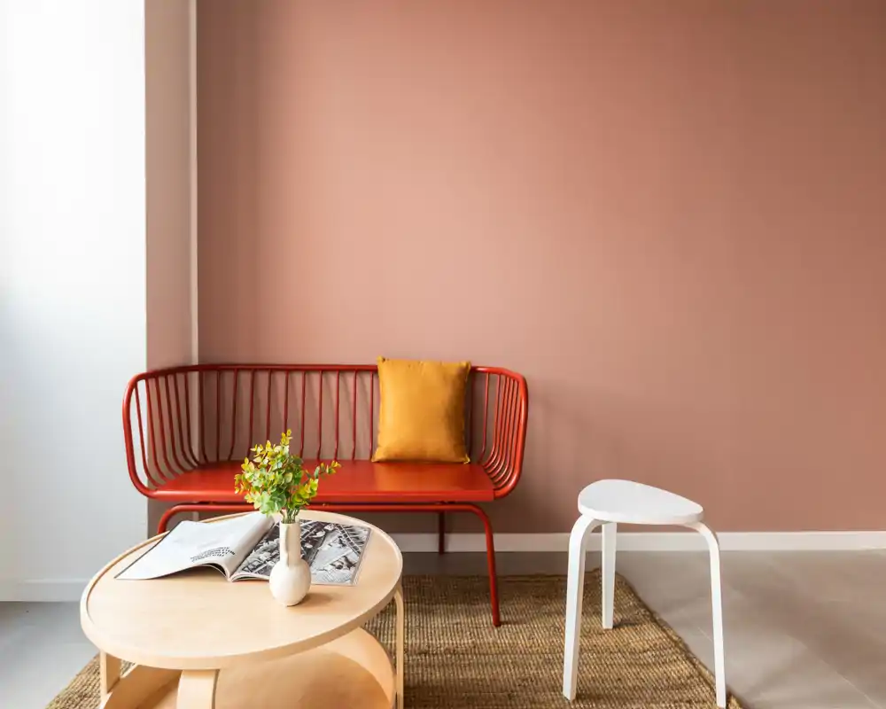 Zona de estar elegante con un sofá banco rojo moderno, cojín de acento cálido y mesas de café minimalistas: un rincón acogedor y bien iluminado para relajarse o leer.