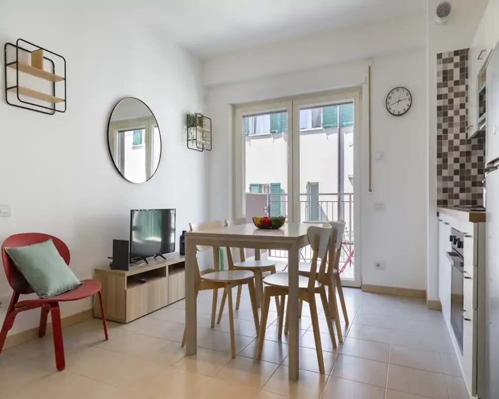 Coin repas moderne et lumineux avec une table en bois et quatre chaises près de grandes baies vitrées ; style minimaliste et lumière naturelle parfaits pour les repas et petites réunions.
