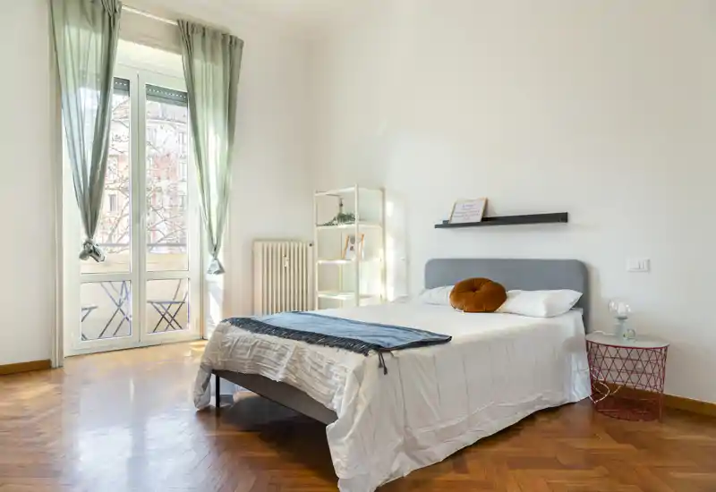 Dormitorio luminoso y aireado con una cómoda cama doble, suelo de parquet y una gran ventana que aporta mucha luz natural.
