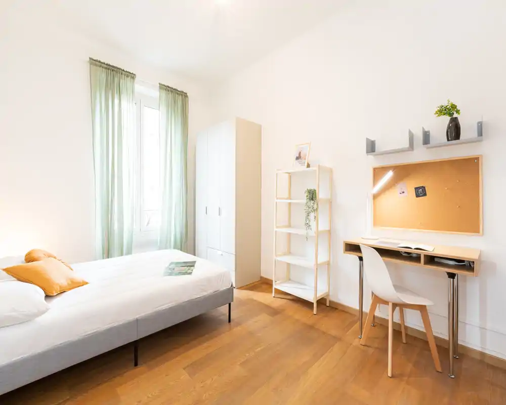 Camera da letto luminosa e ben arredata con letto comodo, angolo studio e armadio — ideale per studenti o viaggiatori singoli.