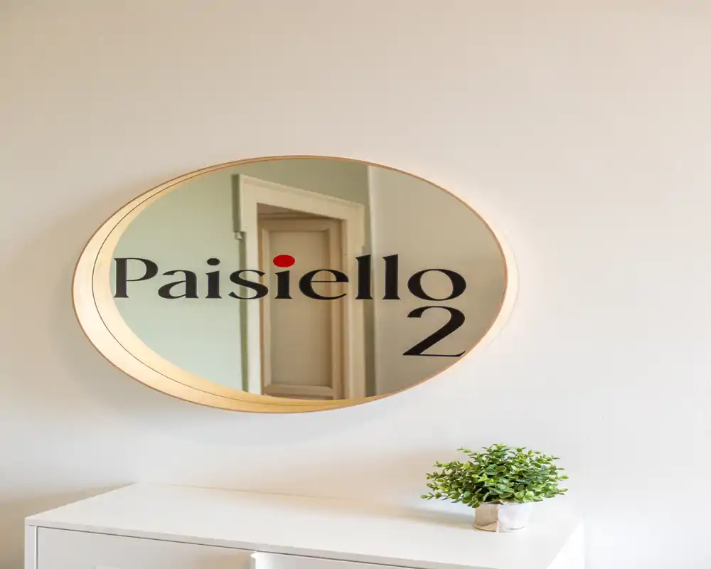 Piccolo ingresso con specchio ovale decorativo e una pianta su un mobiletto — luminoso, ordinato e accogliente.