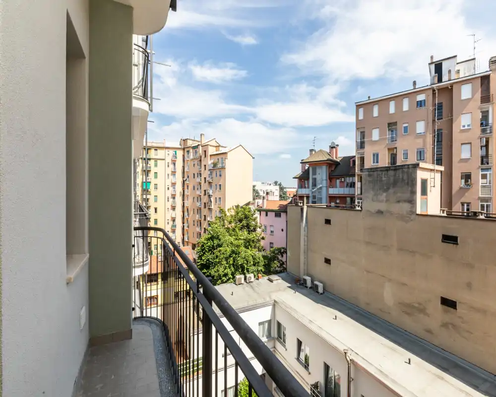 Balcon privé ensoleillé avec garde-corps métallique et vue sur les immeubles voisins — idéal pour un café matinal et la vie citadine.