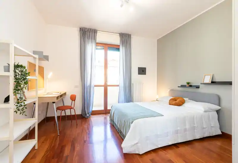 Chambre lumineuse et moderne avec lit double, textiles doux et bureau près de la fenêtre ; parquet chaleureux et murs neutres pour une ambiance apaisante.