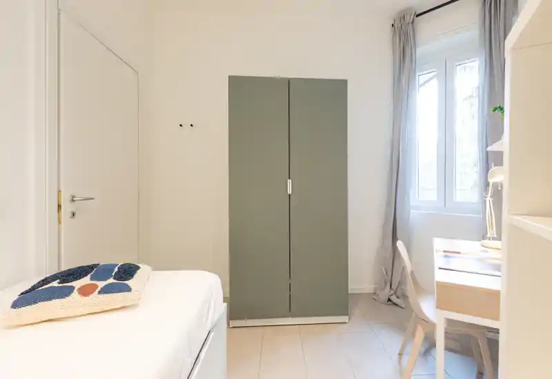 Dormitorio luminoso y minimalista con cama individual, armario y un pequeño escritorio junto a la ventana — estilo moderno y limpio perfecto para un anuncio.