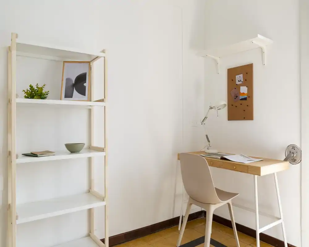 Bright, minimalist home-office corner with a wooden desk, chair, task lamp and open shelving — clean lines and neutral tones create a calm workspace.