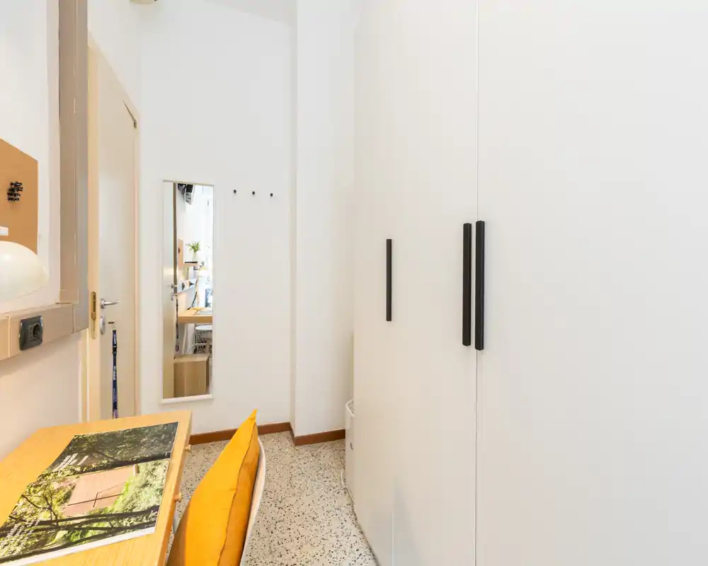 Entrada compacta con armario, espejo en la pared y un pequeño escritorio. Espacio luminoso y ordenado, ideal para guardar abrigos y dejar las llaves al entrar.