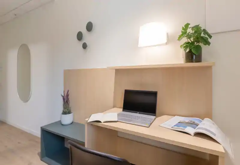 Angolo luminoso e minimale per lavoro/soggiorno con scrivania in legno, laptop e piante decorative; perfetto per concentrarsi in un appartamento moderno.